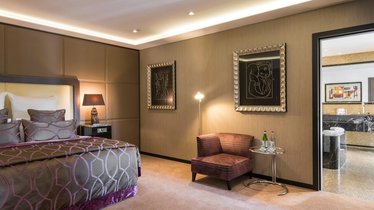 Bed with side table and couch by the doorway in the Grand-Place Suite at Warwick Grand Place Brussels