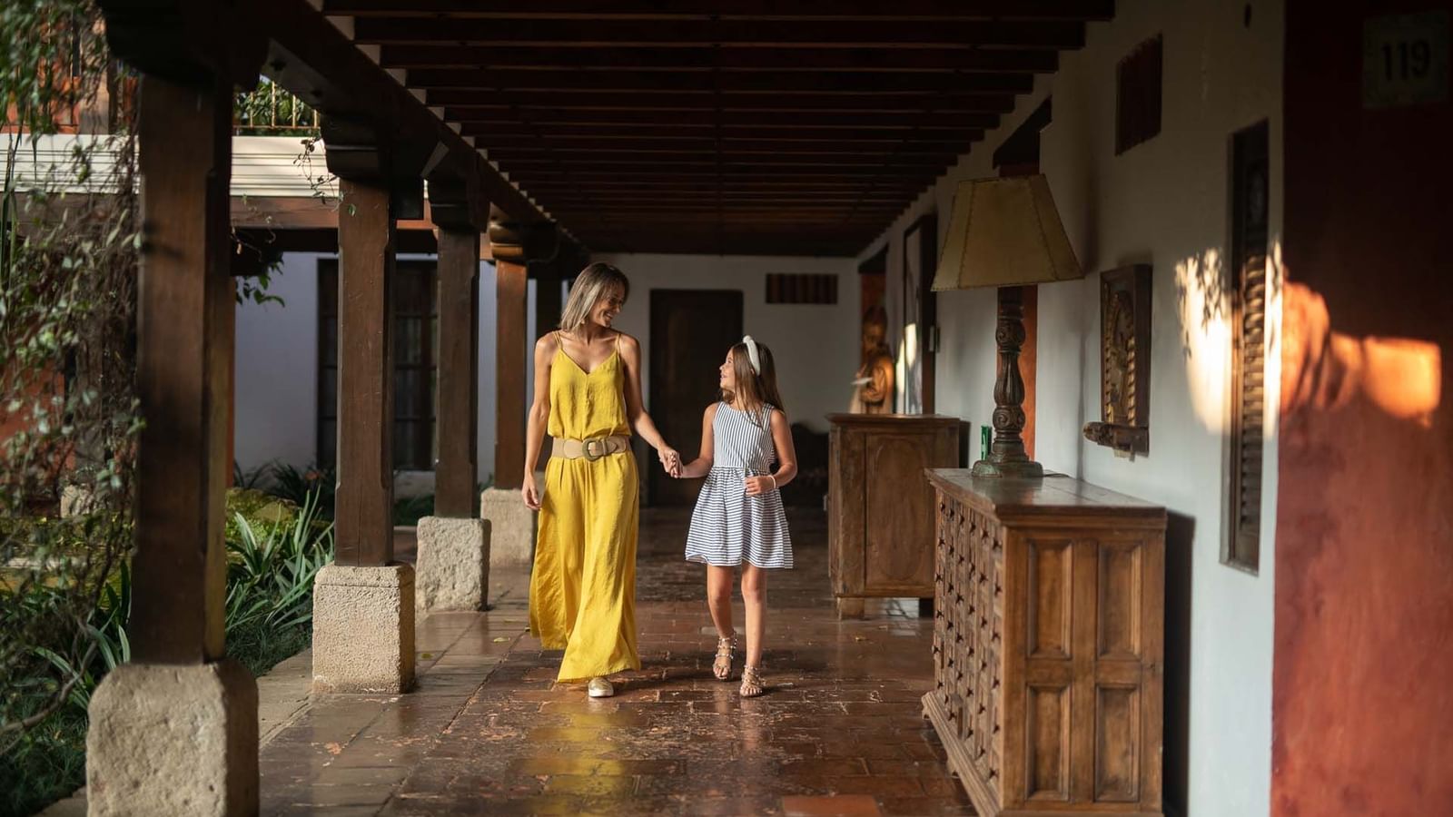 Madre e hija caminando por un encantador pasillo de estilo colonial en Casa Santo Domingo