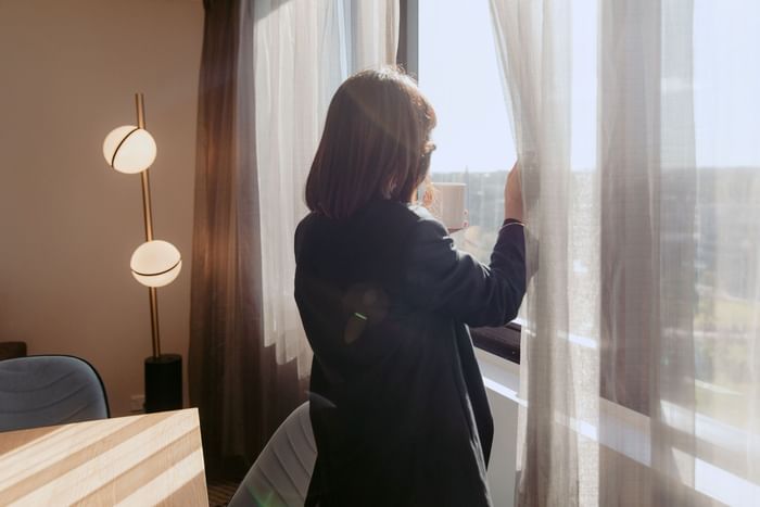Woman looking out of hotel room window at Novotel Sydney Parramatta