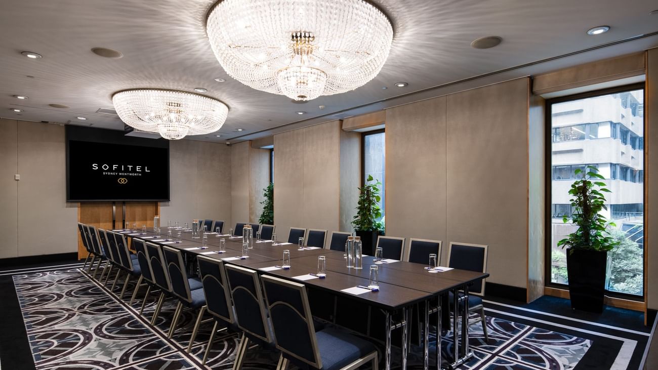 Canberra room boardroom with large conference table, crystal chandeliers and city view windows