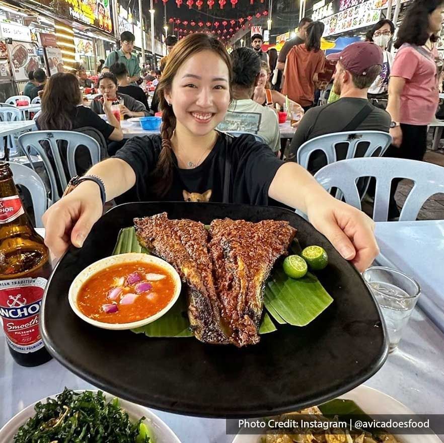 Close-up of lady holding a grilled fish dish in Jalan Alor near Imperial Lexis Kuala Lumpur, Places to eat in KL