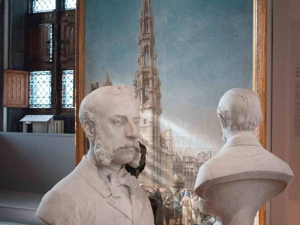 Two bust sculptures in front of a framed artwork in a gallery setting at Hotel In Brussels