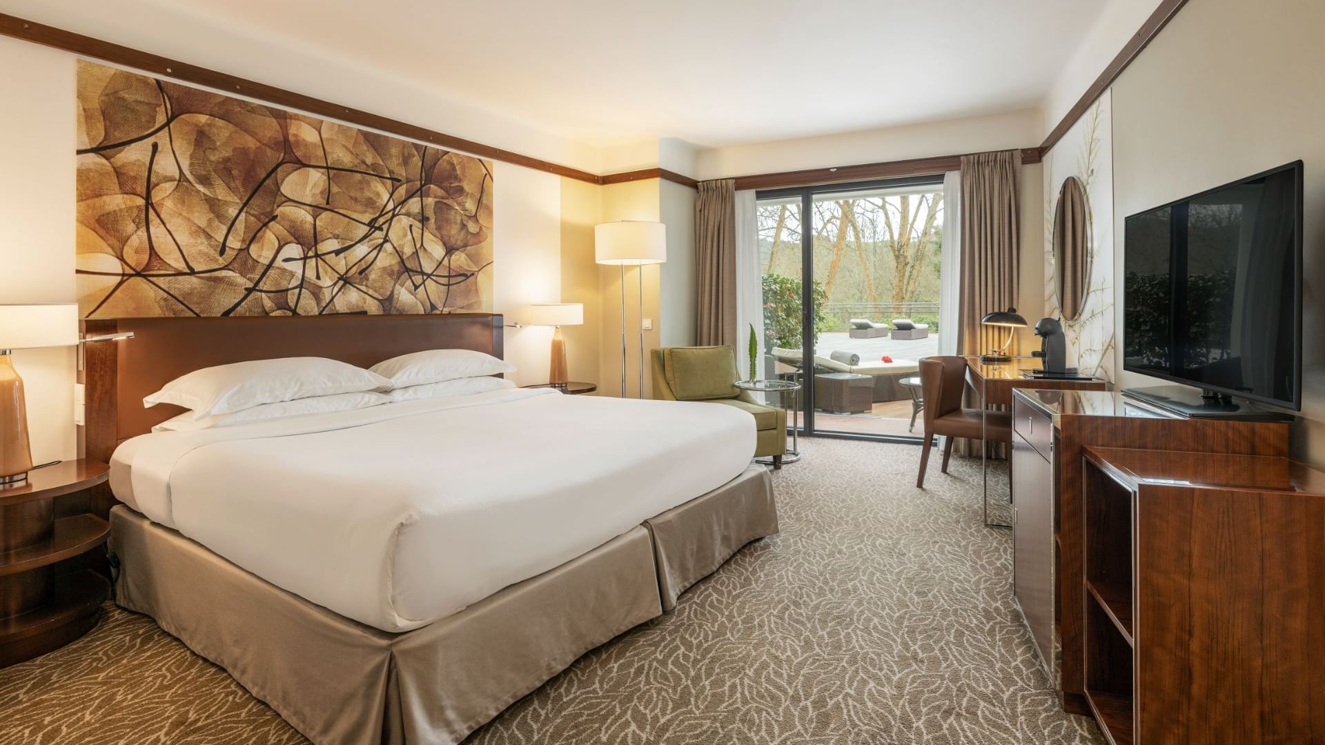 King bed & a TV in Deluxe Garden View Room at Bensaude Hotels