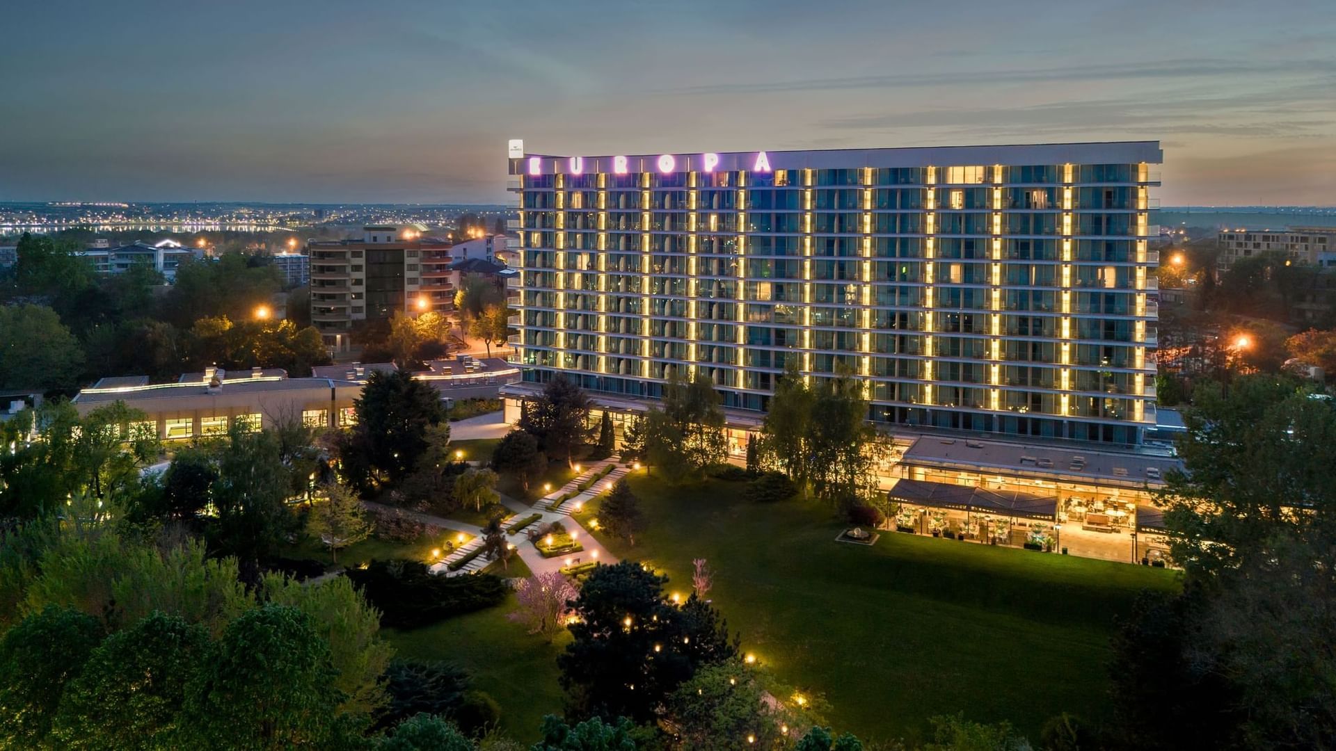 Exterior view of the Ana Hotels Europa Eforie Nord, featuring multiple glass balconies, and lush green landscaping