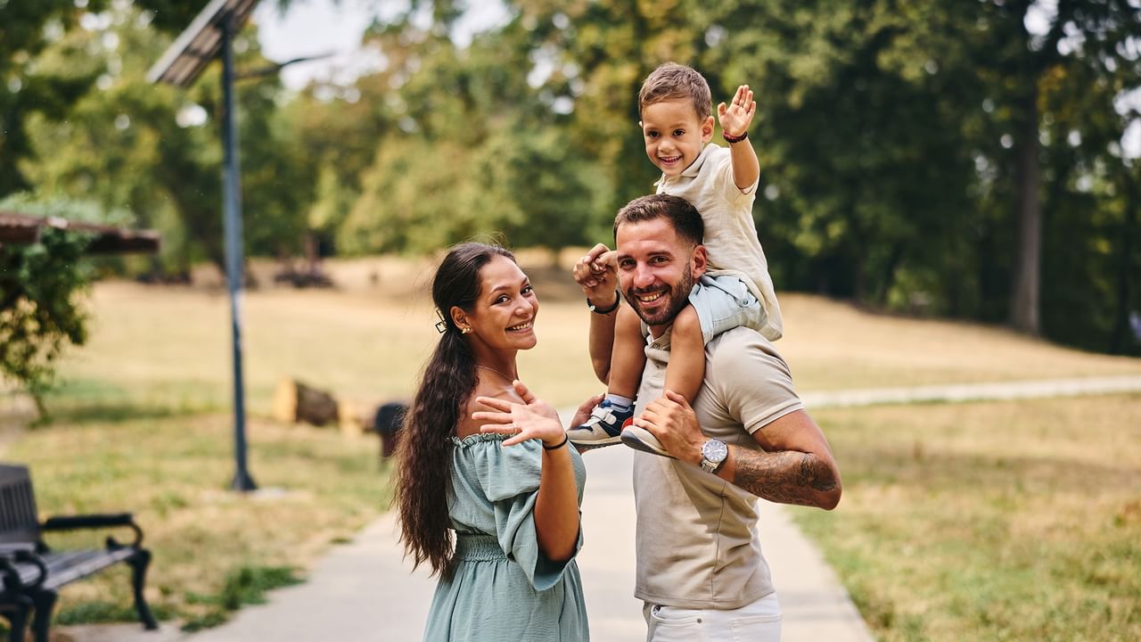 Family enjoying a park with a father carrying his son on his shoulders.