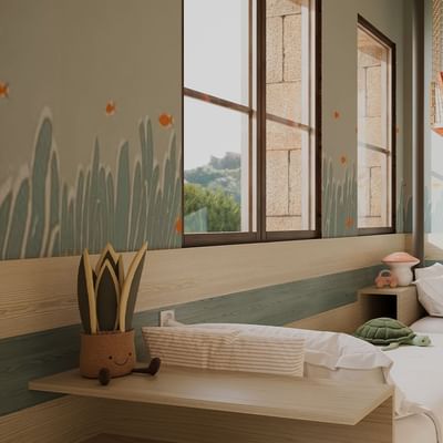 Camera per bambini con due letti singoli, una rete sospesa e decorazioni marine sulle pareti.