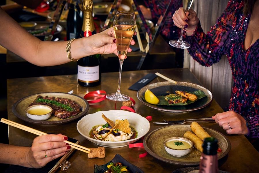 Guests raising champagne glasses over a table filled with various luxury dining dishes at The May Fair Hotel
