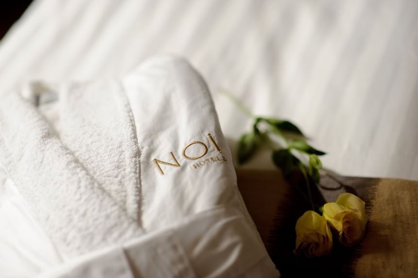 white folded bathrobe & 2 yellow roses at NOI Vitacura hotel  