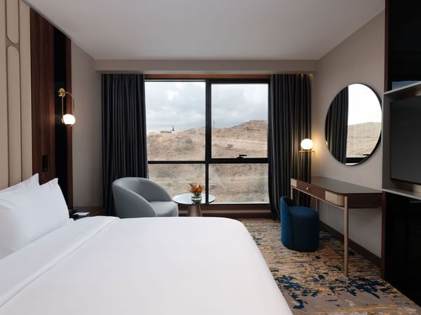 Large bed and armchairs by the window in a room at Warwick Hotel Al Taif