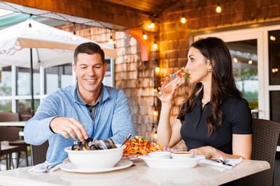 Couple dining at a patio table under warm string lights at Rodd Brudenell River Resort, one of the Best places to stay in PEI