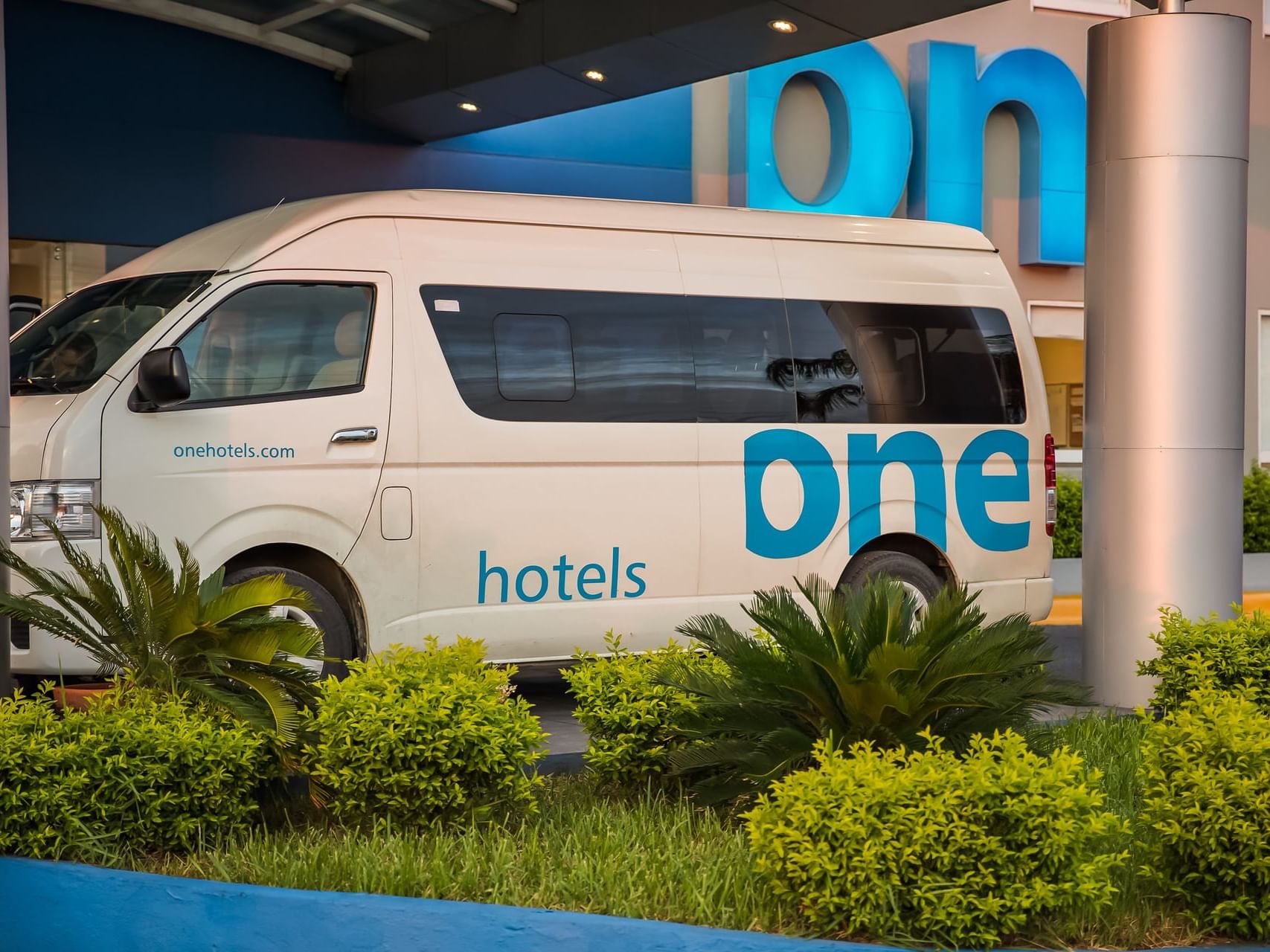 A van from One Hotels Transport service, parked at the entrance
