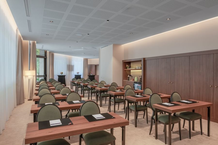 Salle de réunion moderne avec tables en bois et chaises vertes disposées en rangées au Warwick Reine Astrid-Lyon