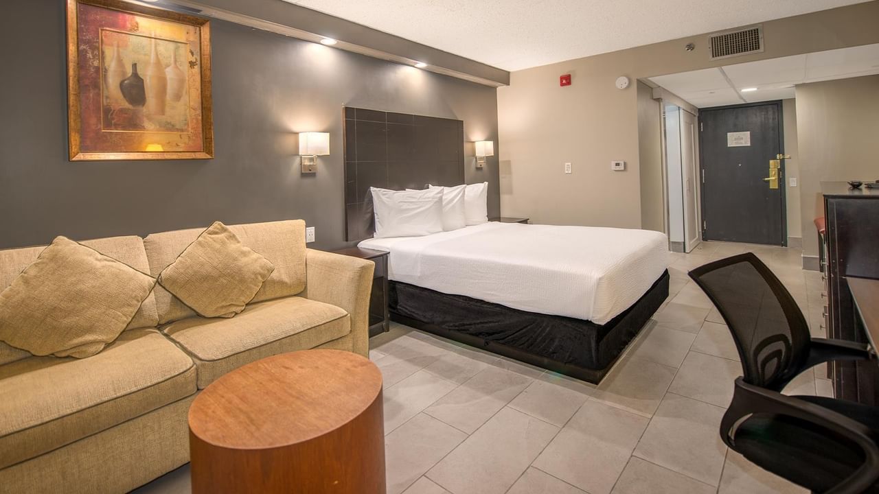 Hotel room with a couch, bed, desk, and chair.