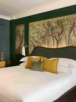 Executive King room with green walls, woodland mural, white bedding, and yellow pillows at The Capital Hotel, Apartments & Townhouse.