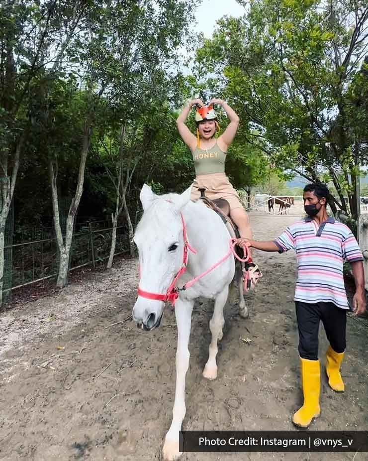 A woman was taking a picture while riding a horse at Countryside Stables in Balik Pulau - Lexis Suites Penang