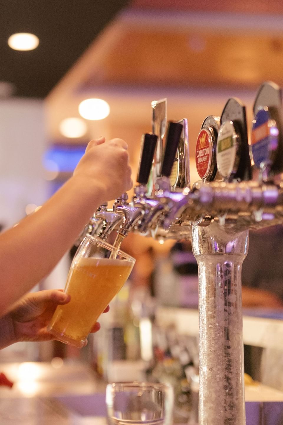 Close up of a hand pouring beer from a tap into a glass in a bar at H on Mitchell