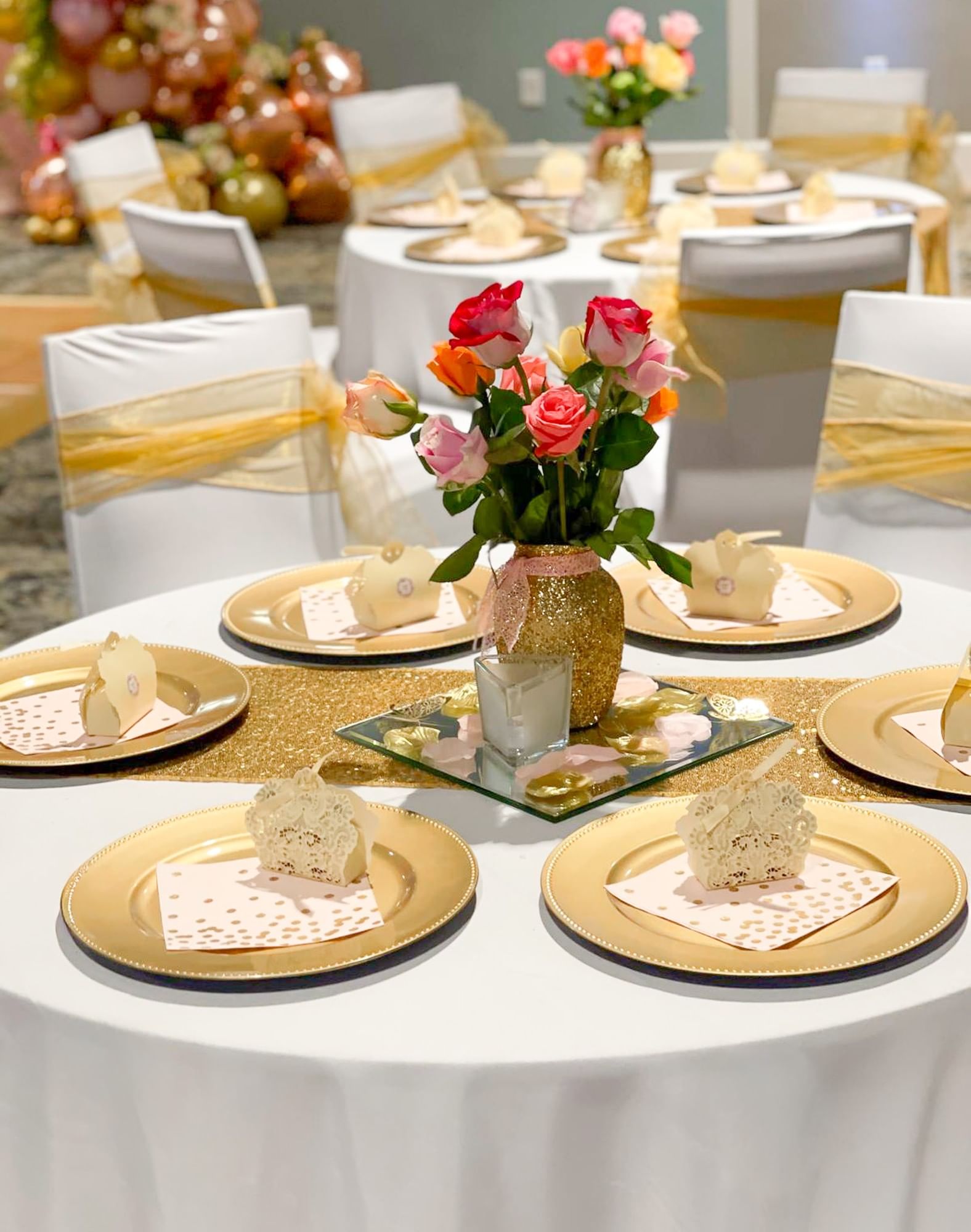 a dining table set with gold plates and flowers