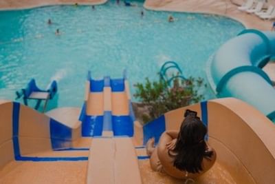 Guest at top of colorful water slide overlooking expansive pool area with swimmers at Playa Blanca Beach Resort NEW SITE