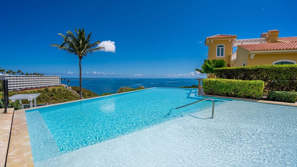 Una piscina infinita con vista al cielo azul y al océano en Las Casitas Village.