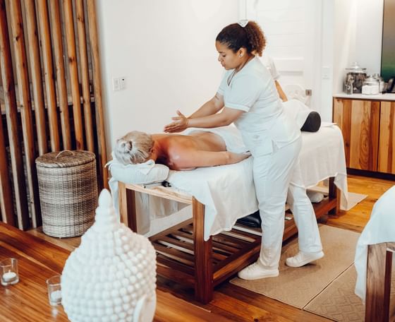 A massage therapist gives a relaxing back massage to a client at the spa at Ibagari Hotel