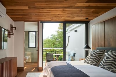 Bedroom with a large bed, wooden furniture, and a balcony with a small table in Casa Cielo at Singular Signature Residences