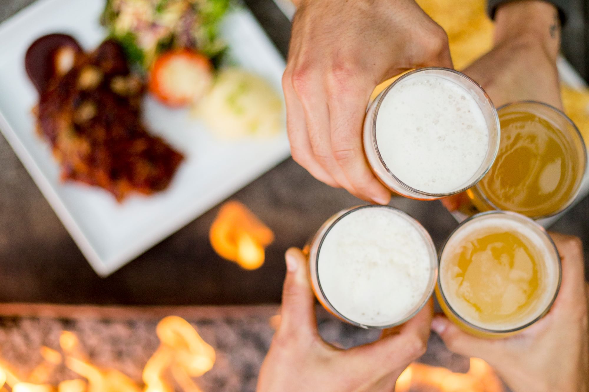 Close-up of four people toasting beers for Whistler Craft Beer month near Blackcomb Springs Suites