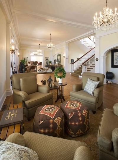 A spacious and elegantly decorated common area at The Stanley Hotel with armchairs a grand staircase and chandeliers