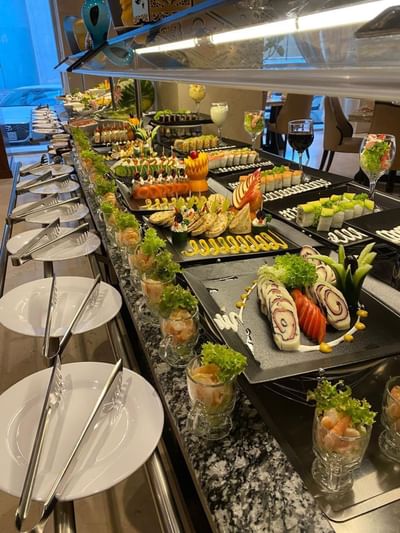 Buffet spread featuring sushi rolls by appetizers on black platters in Royal Restaurant at Naviti by Warwick Al Khobar