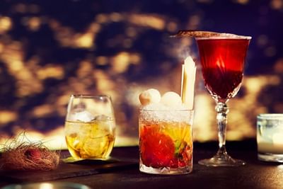 Three stylish cocktails on a black bar counter in the 2 Lam Son Bar at Park Hyatt Saigon
