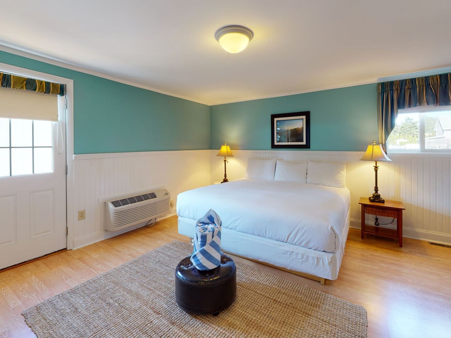 Bed with table lamp by the door and wooden floors in Main House Two-Bedroom Deluxe at Breezeway Boutique Hotel