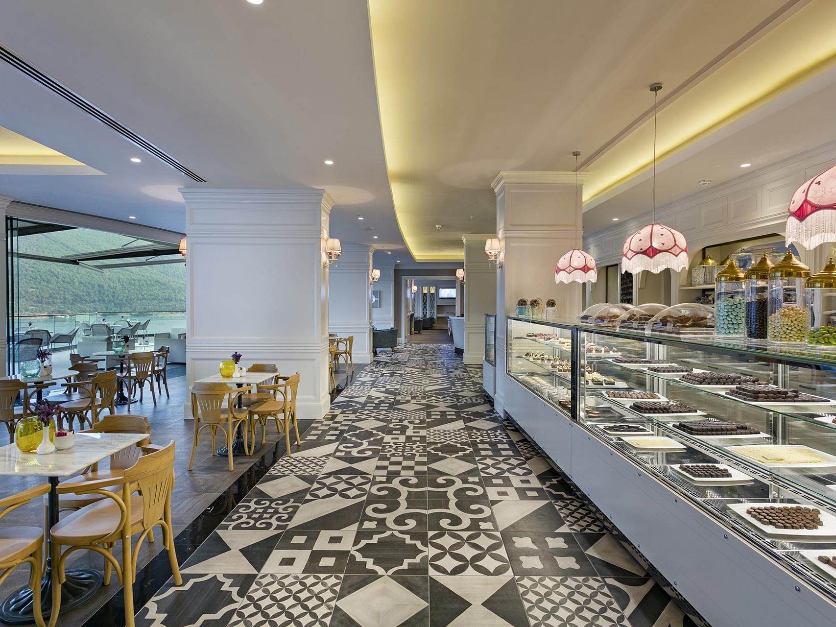 A chic restaurant interior at Titanic Luxury Collection Bodrum, featuring a large chocolate display and patterned flooring.