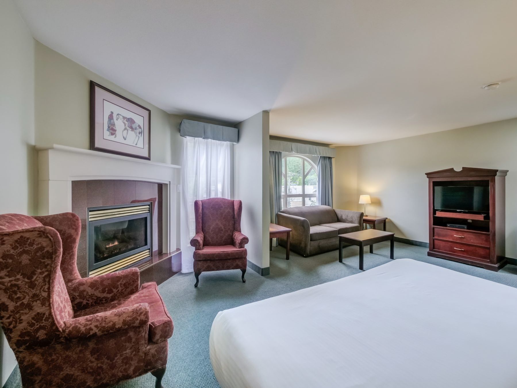 bed in cozy room with fireplace and chairs
