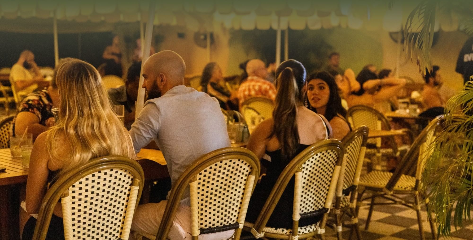A group of people sitting at tables in an outdoor dining area.