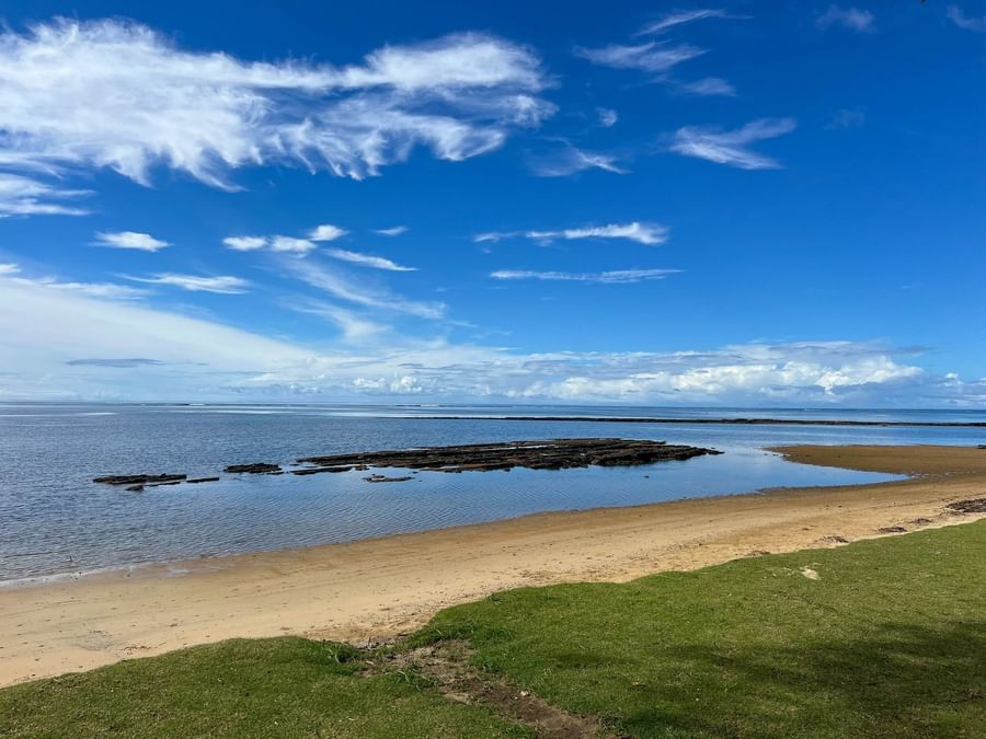 Sandy beach with ocean and blue sky at The Naviti Resort Fiji.