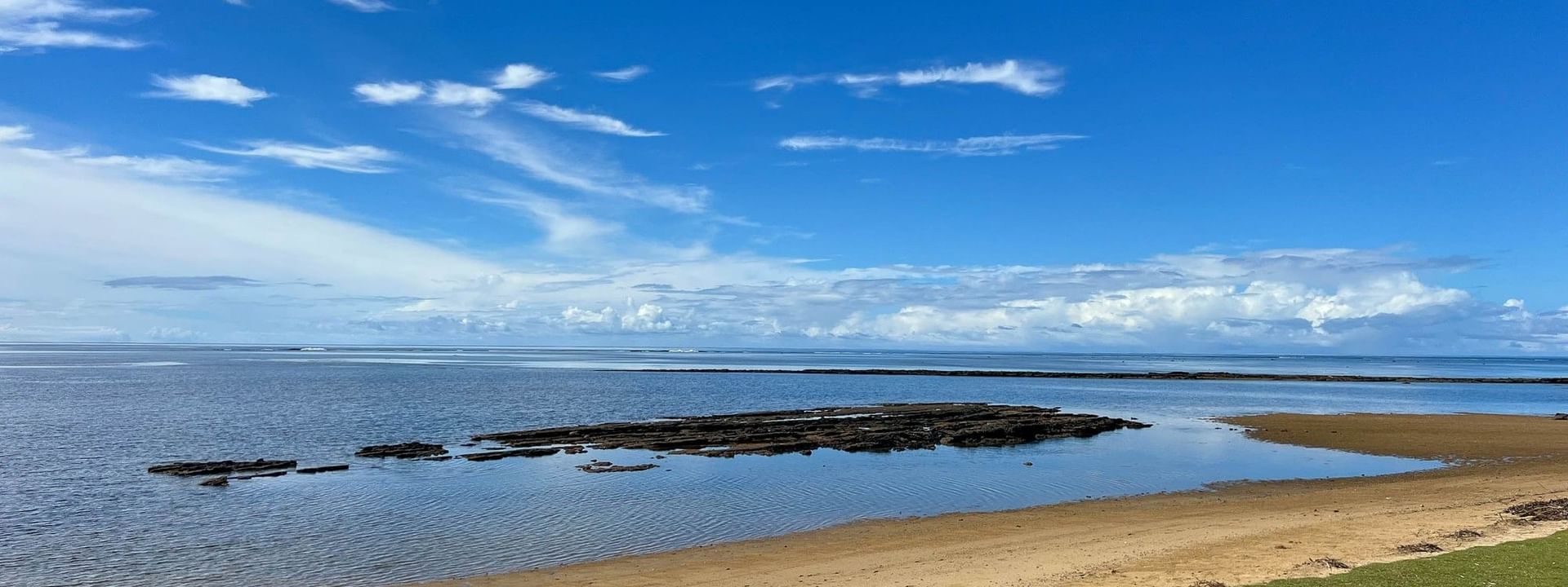 Sandy beach with rocky shoreline under a blue sky at The Naviti Resort in Korolevu, Fiji