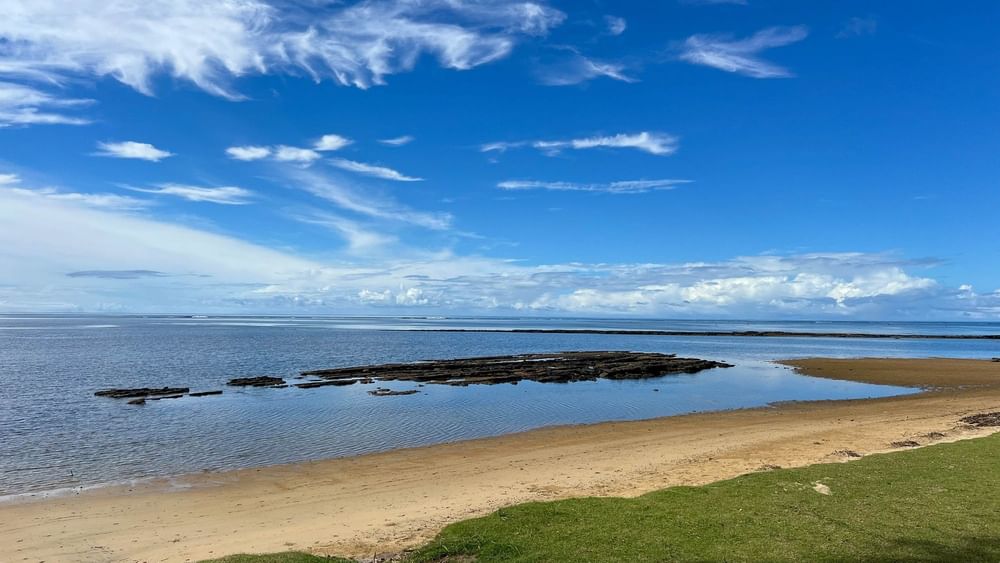 Sandy beach with rocky shoreline under a blue sky at The Naviti Resort in Korolevu, Fiji.