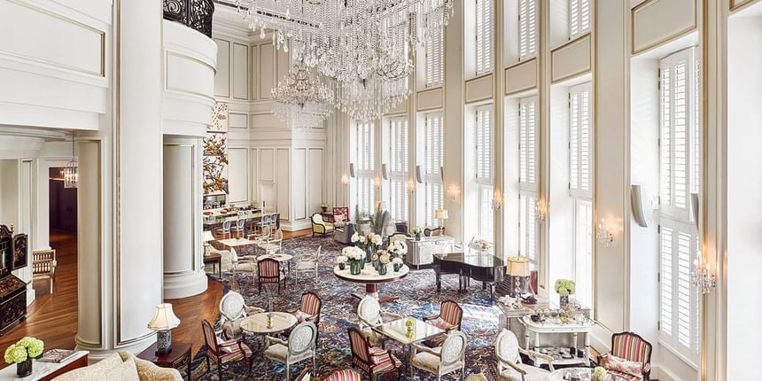 Dining area with a grand chandelier, ornate furniture, and large windows in Park Lounge at Park Hyatt Saigon