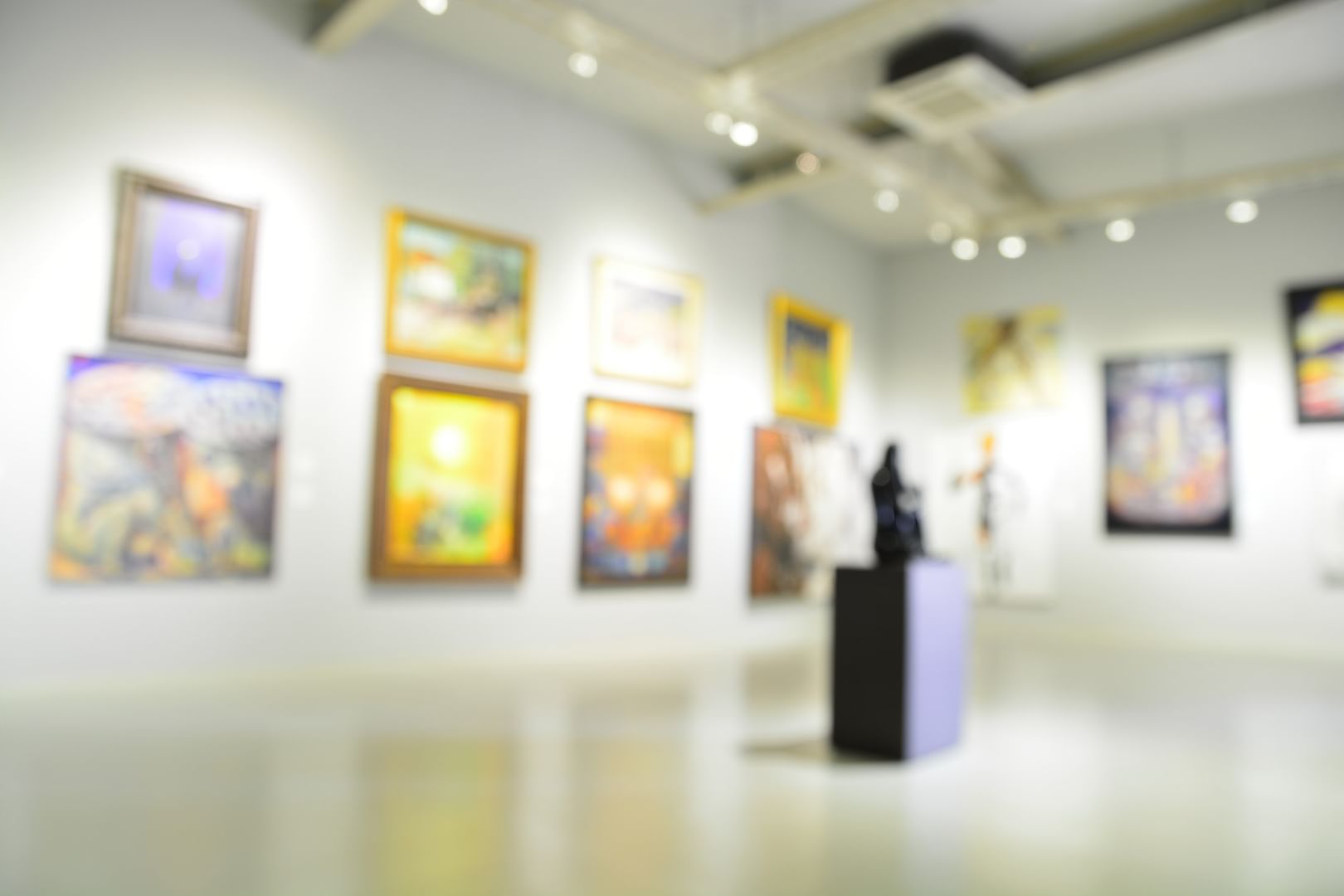Framed paintings on white walls surrounding a dark sculpture in a gallery in Museum at Warwick Melrose Dallas