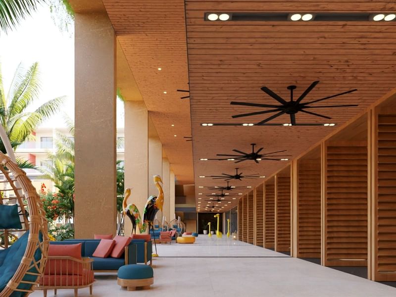 Largo pasillo exterior en Fiesta Americana Funeeq con techos de madera, ventiladores grandes y sillones modernos