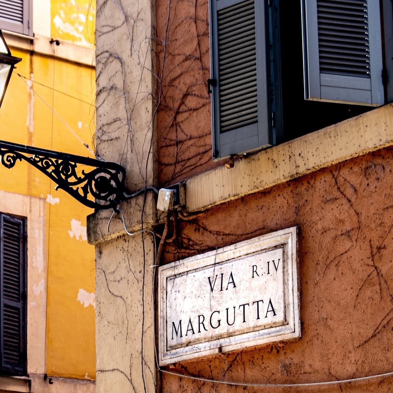 Ornate street lamp and Via Margutta sign on peeling wall near Rome Luxury Suites