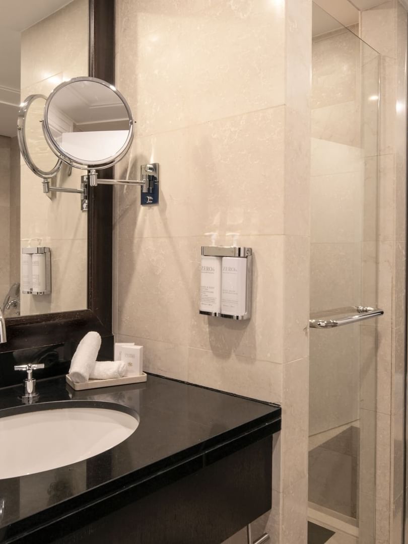 White sink in a black vanity by a glass shower door in The Montaigne Suite at Warwick Paris Champs Elysées