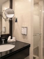 White sink in a black vanity by a glass shower door in The Montaigne Suite at Warwick Paris Champs Elysées
