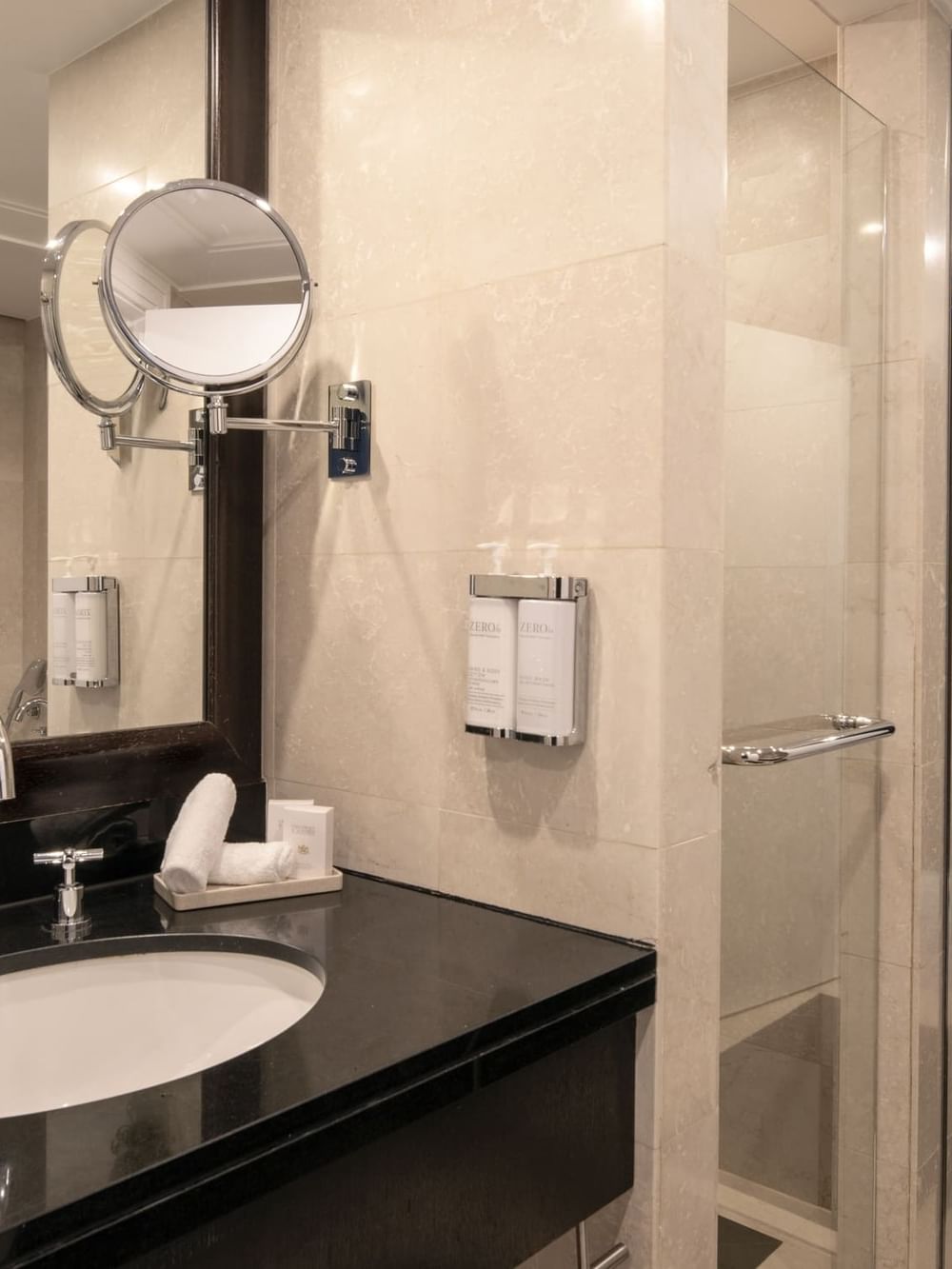 White sink in a black vanity by a glass shower door in The Montaigne Suite at Warwick Paris Champs Elysées