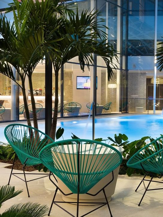 Piscine extérieure avec espace assis et palmiers à Oceania Paris Roissy CDG