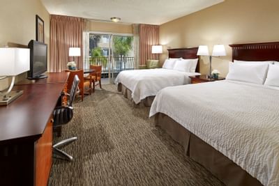 TV with work desk facing bed near the window in 2 Queen Deluxe Rooms at Anaheim Portofino Inn & Suites