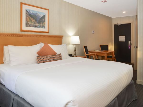 Spacious hotel room with a king bed and elegant decor.