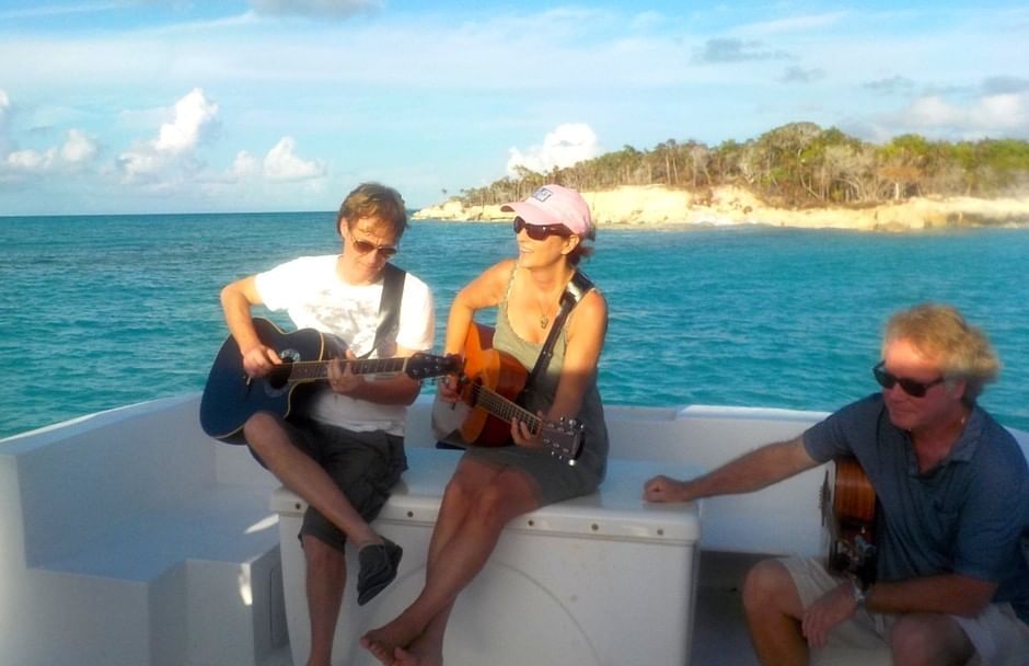 Couple playing guitar in a boat near The Somerset on Grace Bay
