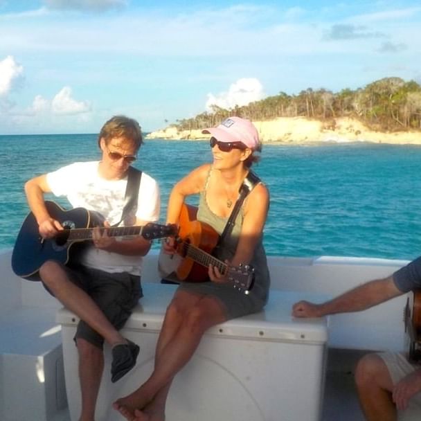 Couple playing guitar in a boat near The Somerset on Grace Bay