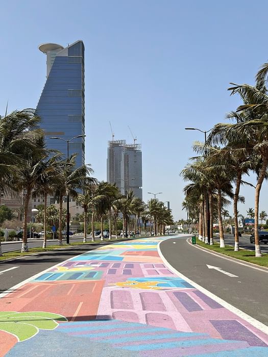 Street mural along a palm tree road on Jeddah Corniche near Naviti by Warwick, capturing vibrant places to explore Jeddah