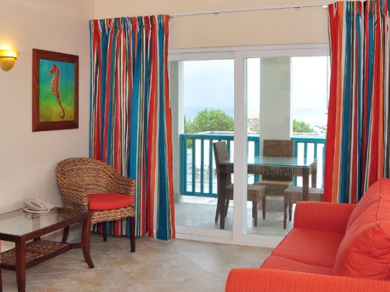 Colorful curtains, wicker furniture and balcony with sea view in Deluxe Island View One Bedroom at Rostrevor Hotel